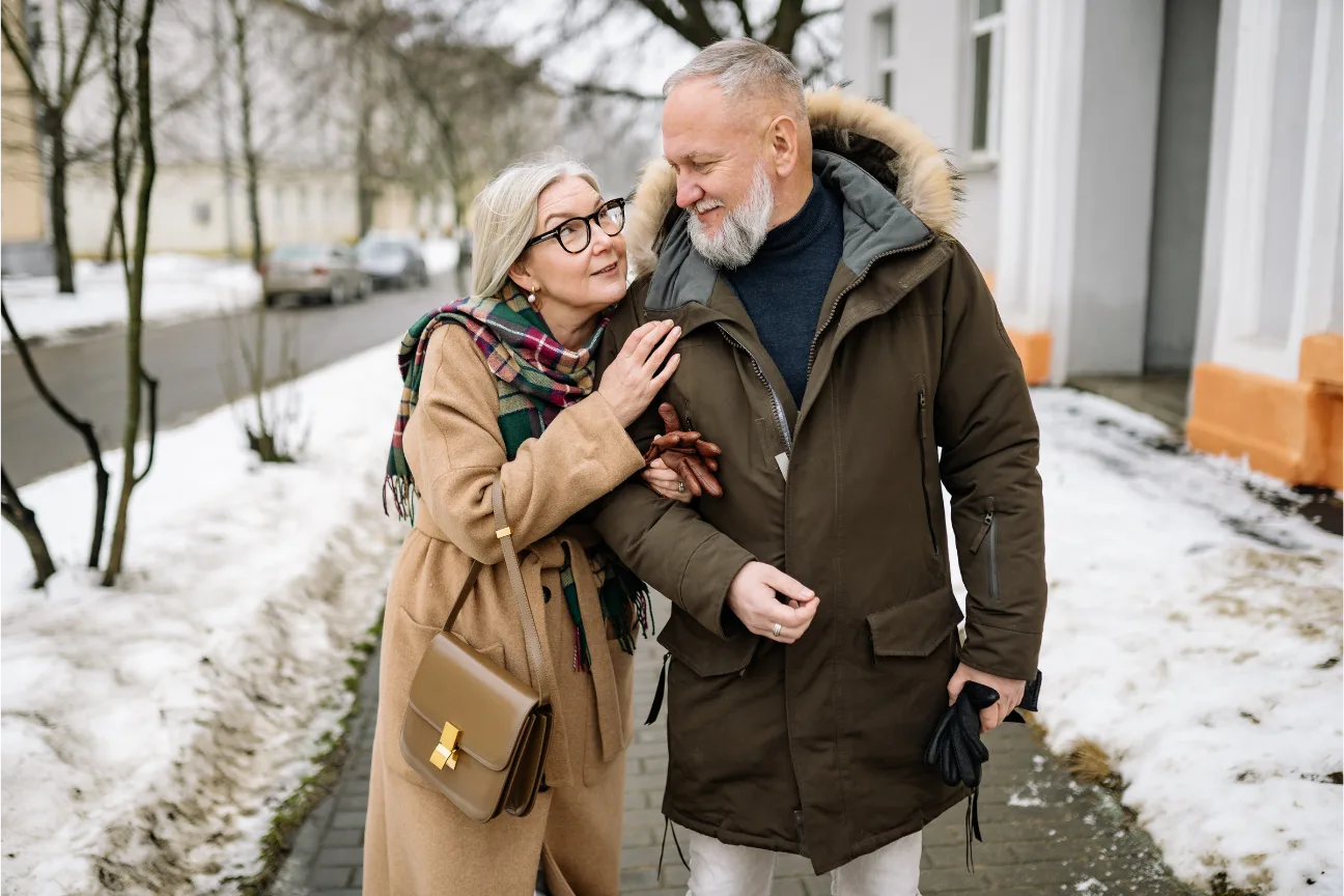 An older couple walking arm in arm outdoors.